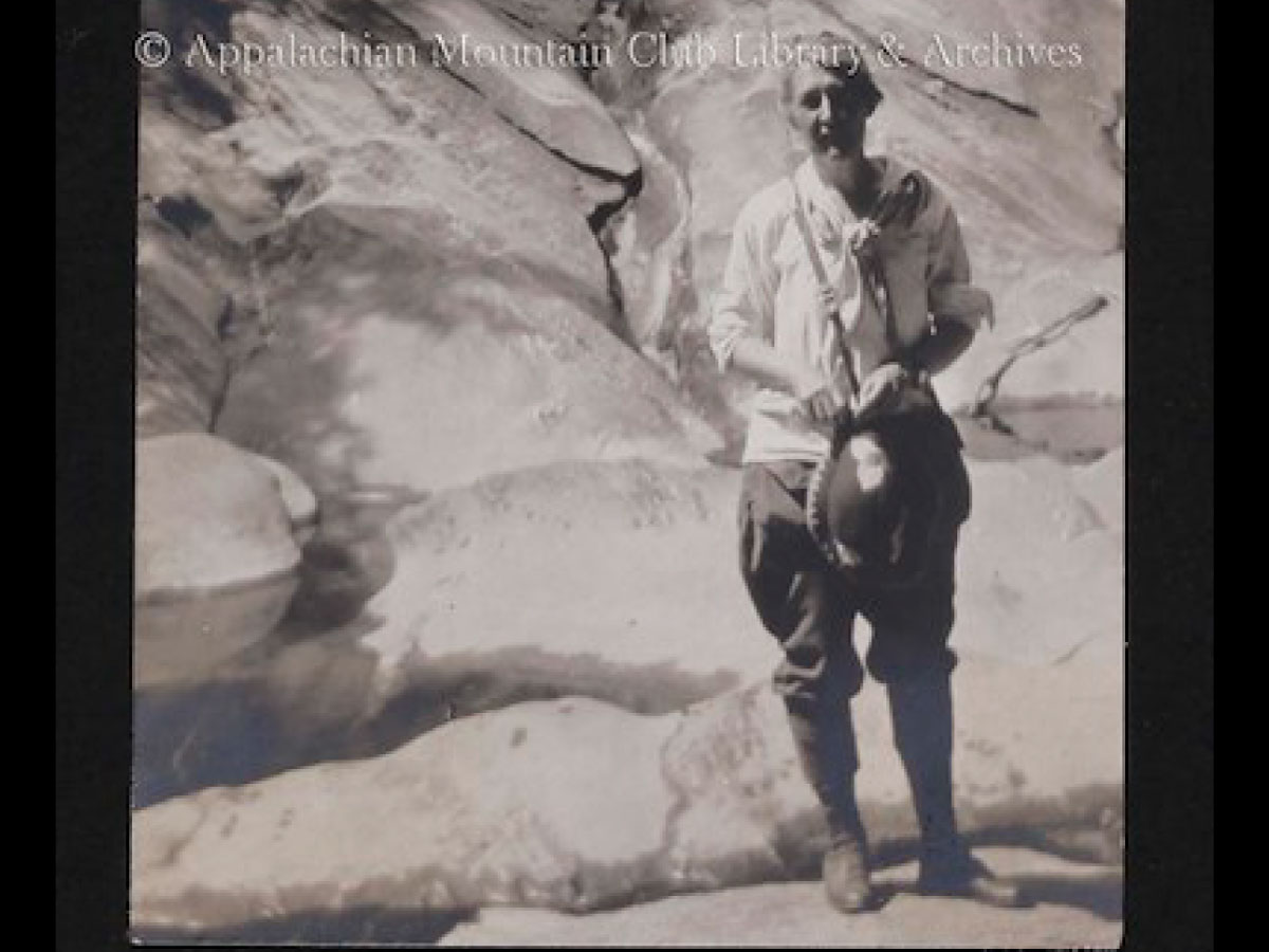 A hiker stands at a cave