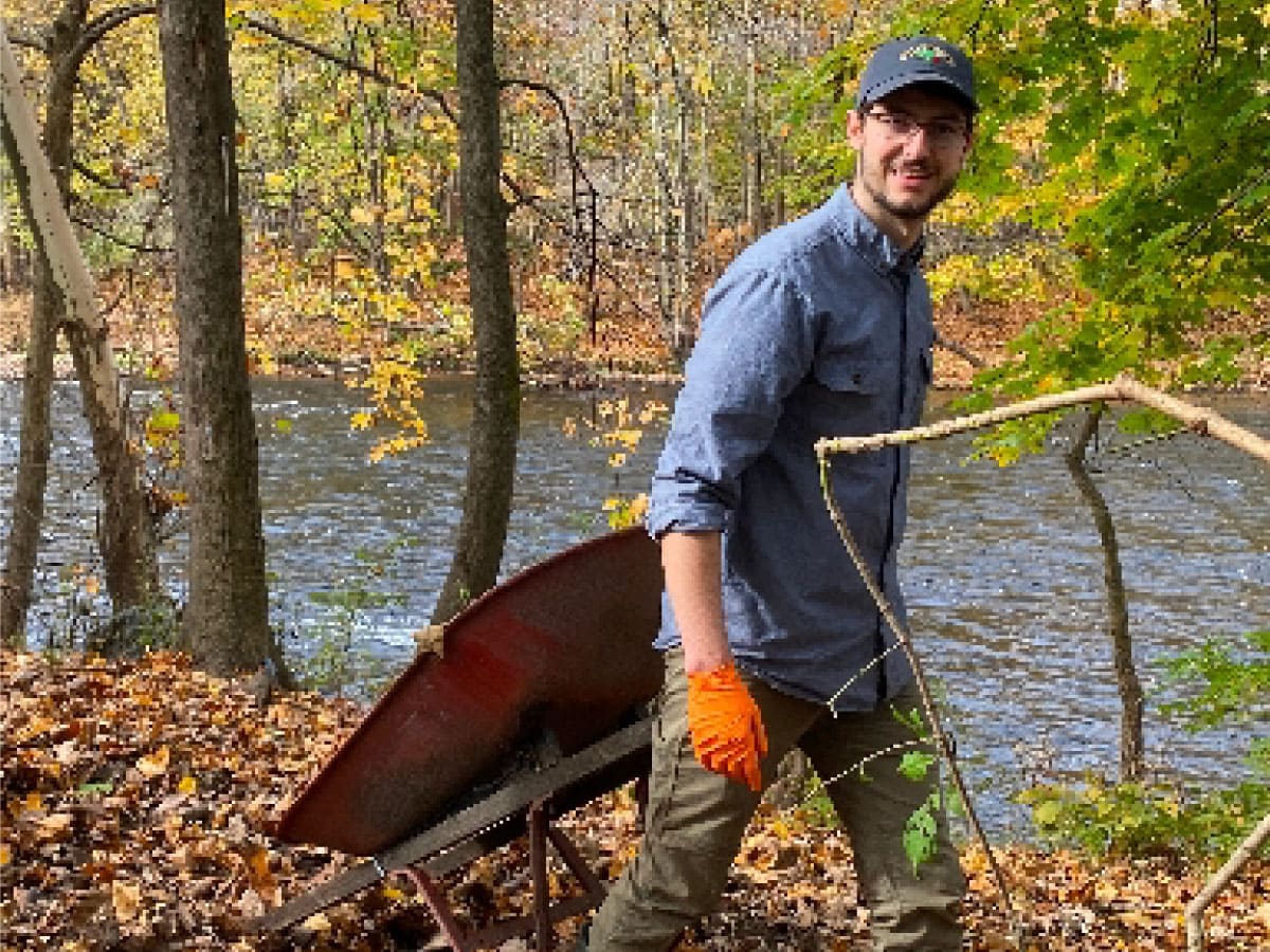 A volunteer clears trash from a riverbank