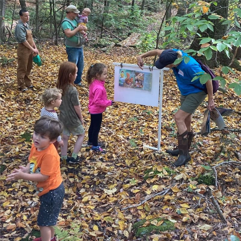 A naturalist shows children the StoryWalk at Noble View