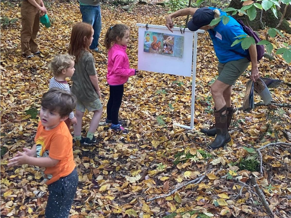 A guide shows a StoryWalkÂ® book to children